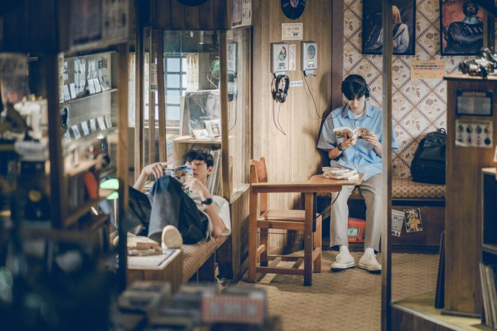 still from a time called you drama showing two boys reading comic books in a record store