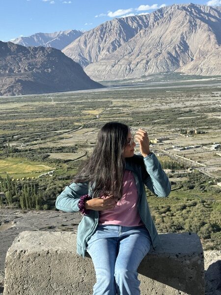 photo of me in ladakh wearing green fleece jacket, pink shirt, and blue pants