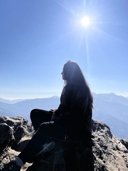 photo of me sitting on a rock with the mountains and sun behind me