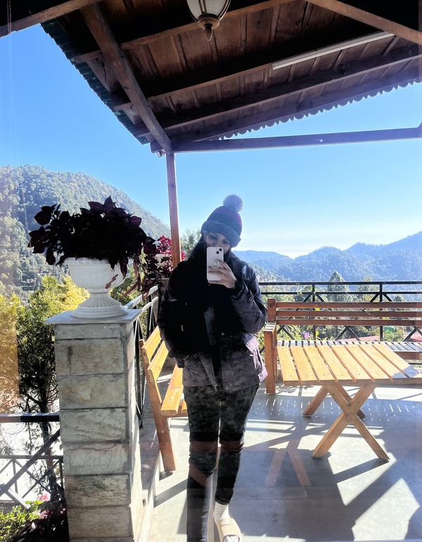 a photo of me at our Bhimtal stay with the mountains in the background