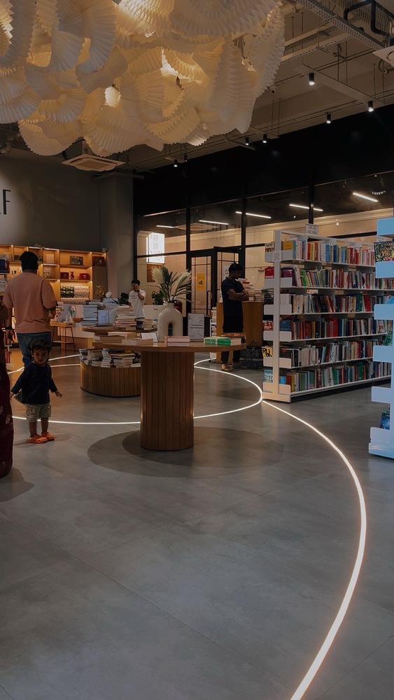 picture of the bookstore showing shelves and a table displaying select books and people browsing the books